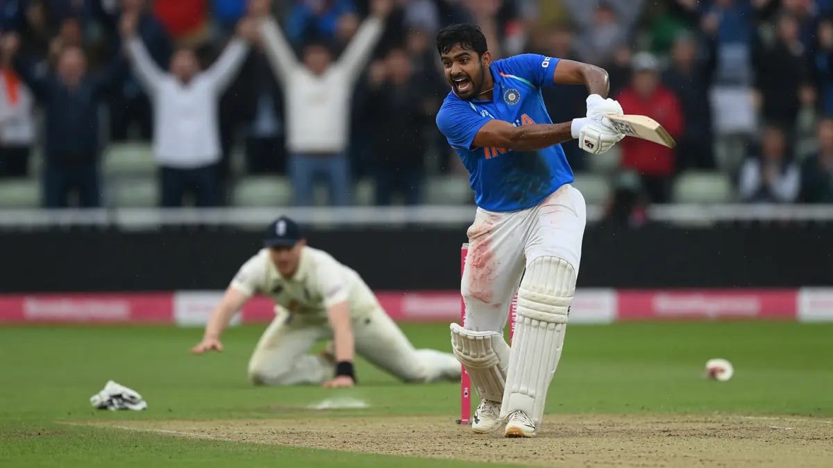 India batter in blue jersey celebrating a shot while an England fielder in white slides on the outfield